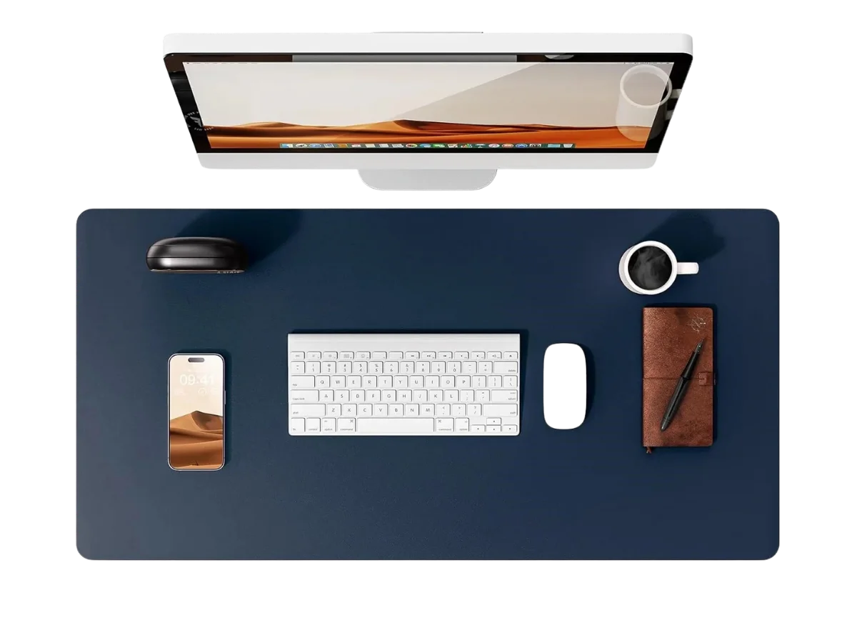 Vue de dessus d'un bureau avec un grand tapis de souris cuir bleu marine, clavier, souris, téléphone et tasse de café.