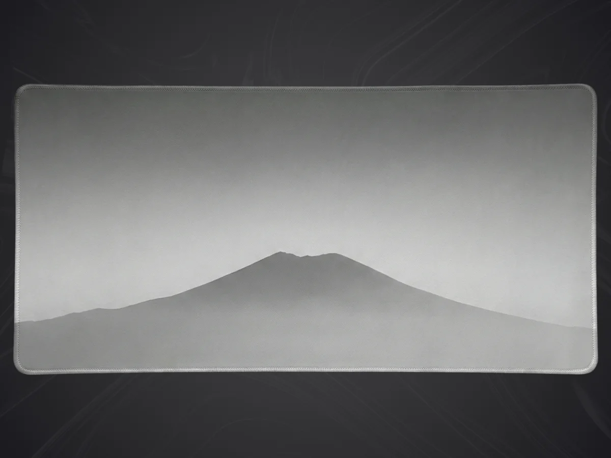 Grand tapis de souris minimaliste gris avec un dessin stylisé de montagne en niveaux de gris et bords cousus.